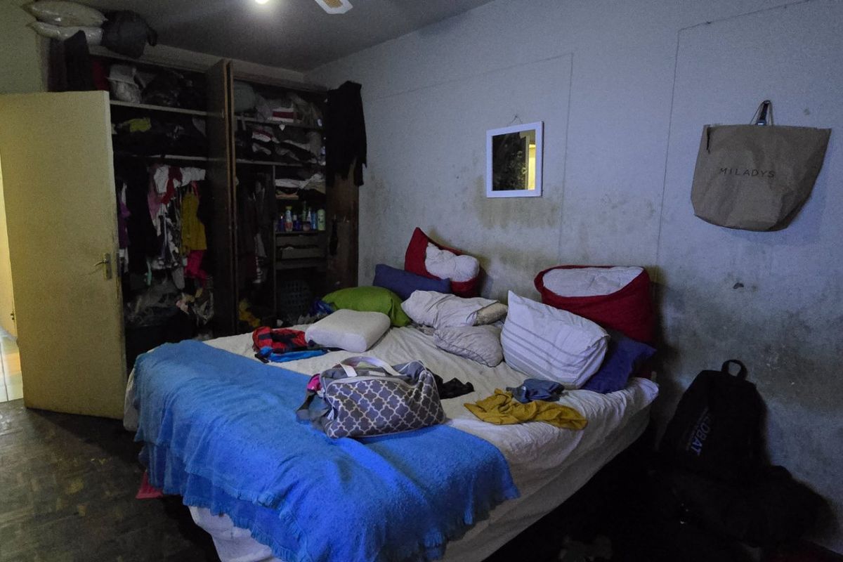 A bedroom featuring a built-in wardrobe, currently showing significant wall staining and discoloration requiring maintenance.
