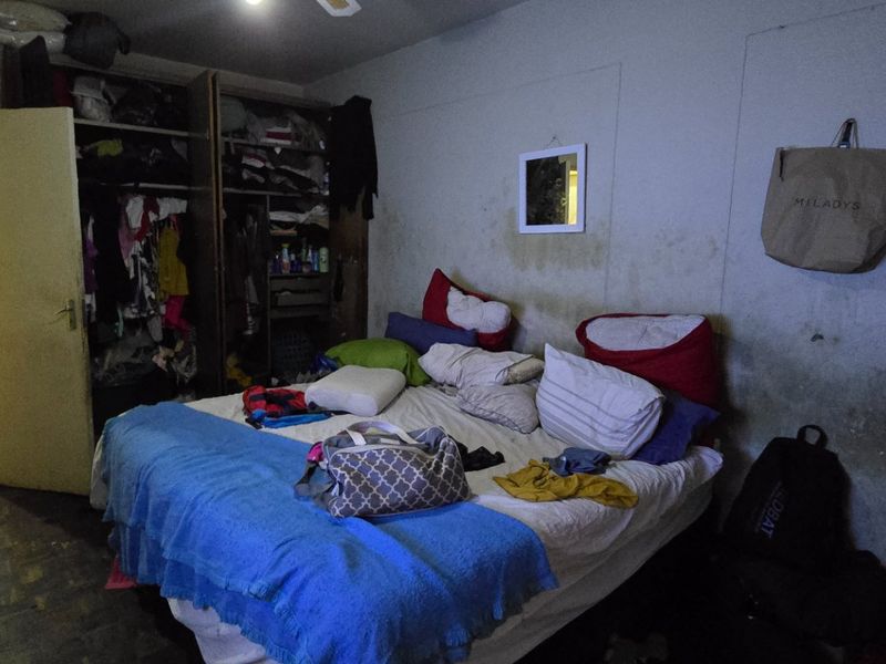 A bedroom featuring a built-in wardrobe, currently showing significant wall staining and discoloration requiring maintenance.
