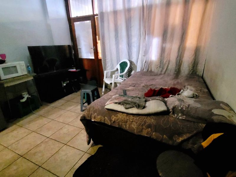 A bedroom featuring tiled flooring and a sliding glass door, currently showing signs of wear and requiring cosmetic updates.