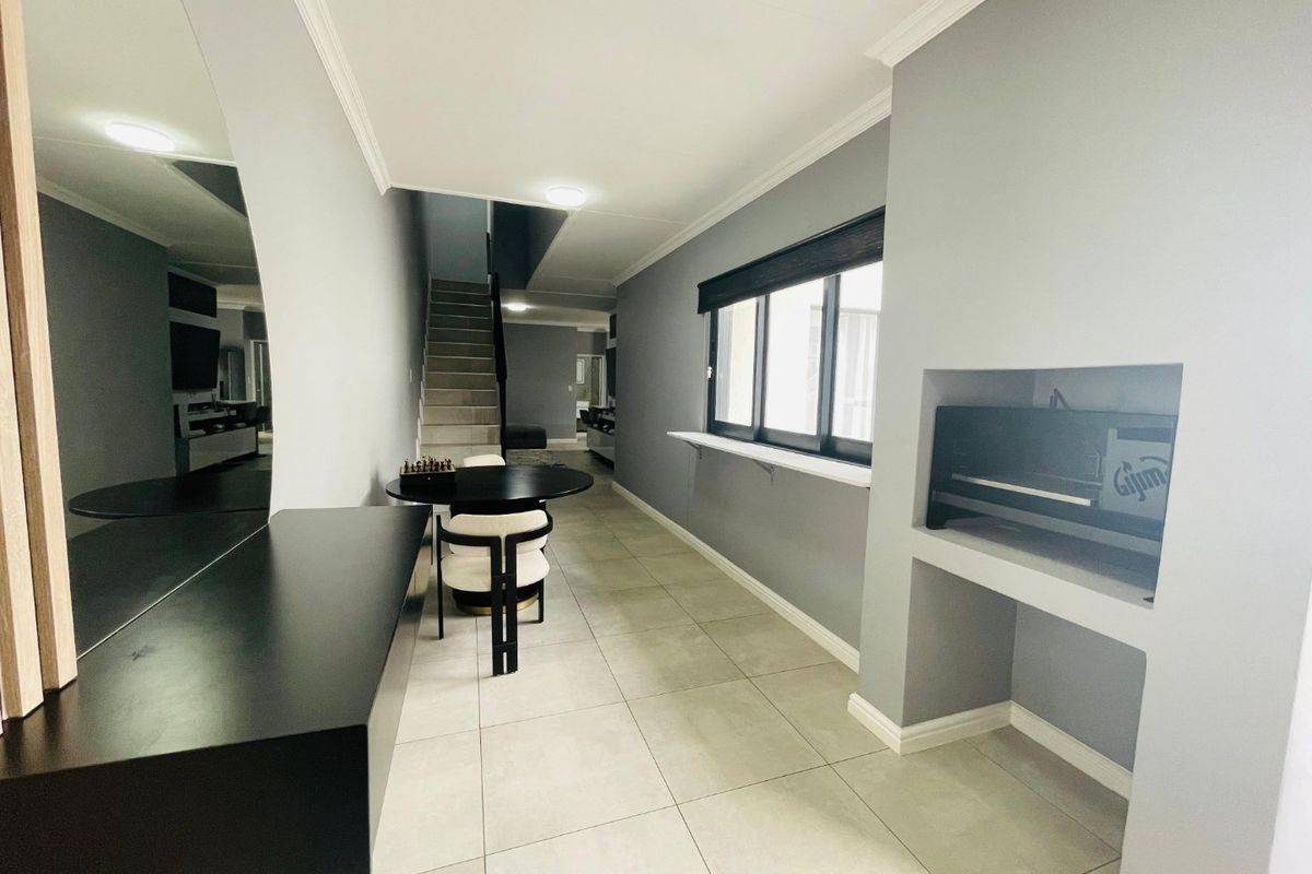 Modern living area featuring neutral grey walls, tiled flooring, a built-in fireplace, and a staircase leading to the upper level.