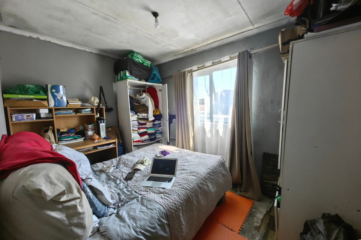 A bedroom featuring a window with curtain rails, requiring cosmetic updates to the ceiling and flooring to improve the overall condition.