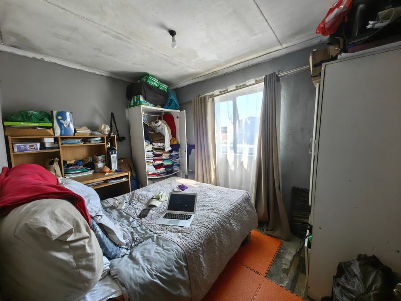 A bedroom featuring a window with curtain rails, requiring cosmetic updates to the ceiling and flooring to improve the overall condition.