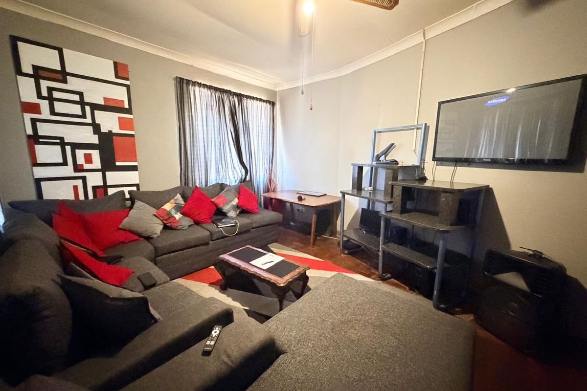 A living room featuring hardwood flooring, coving, and a ceiling fan, providing a functional space for relaxation.