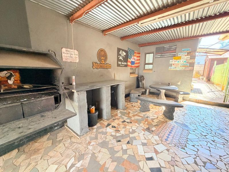 Covered outdoor patio area featuring a built-in braai, concrete prep counter, and durable crazy paving flooring, ideal for casual outdoor entertaining.