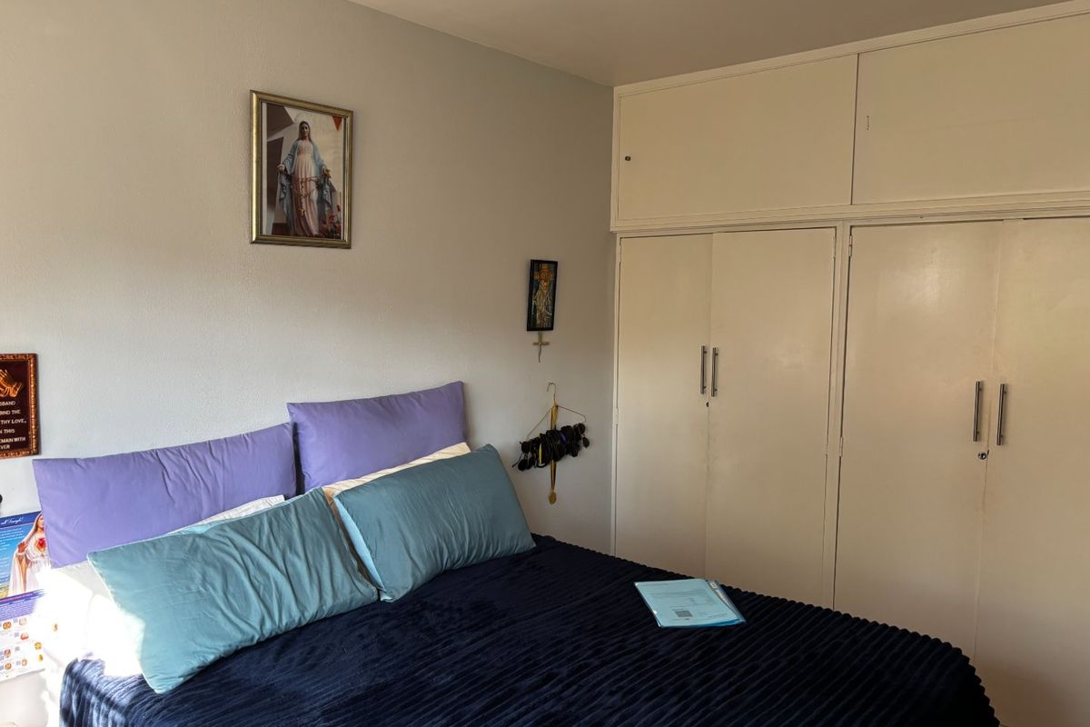 A bedroom featuring built-in cupboards with integrated overhead storage cabinets, providing functional storage space.