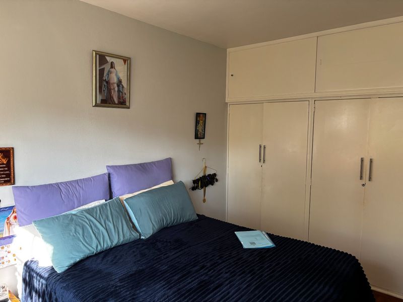 A bedroom featuring built-in cupboards with integrated overhead storage cabinets, providing functional storage space.
