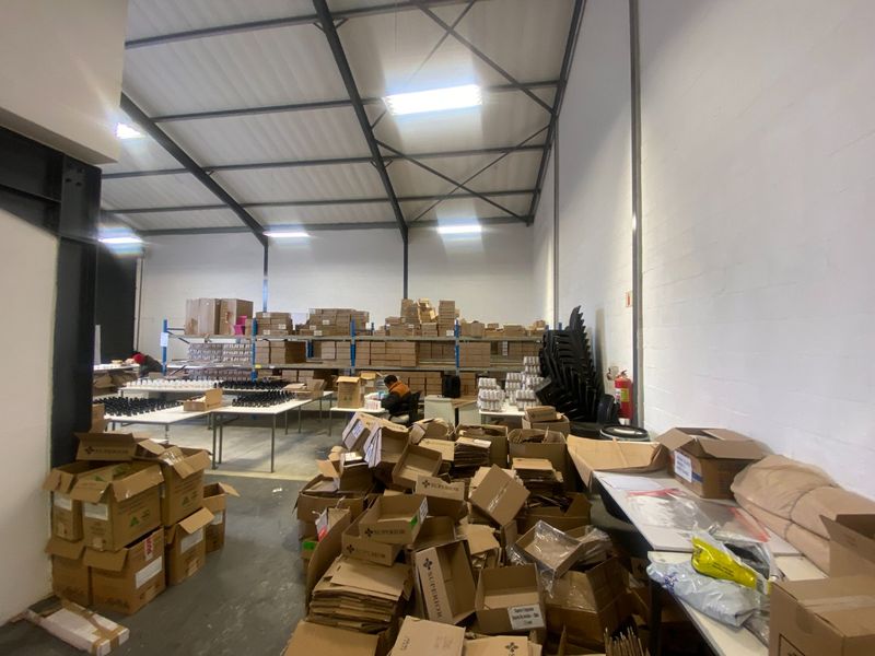 Spacious industrial warehouse or utility area featuring high exposed steel roof trusses, concrete flooring, and integrated metal shelving for storage.