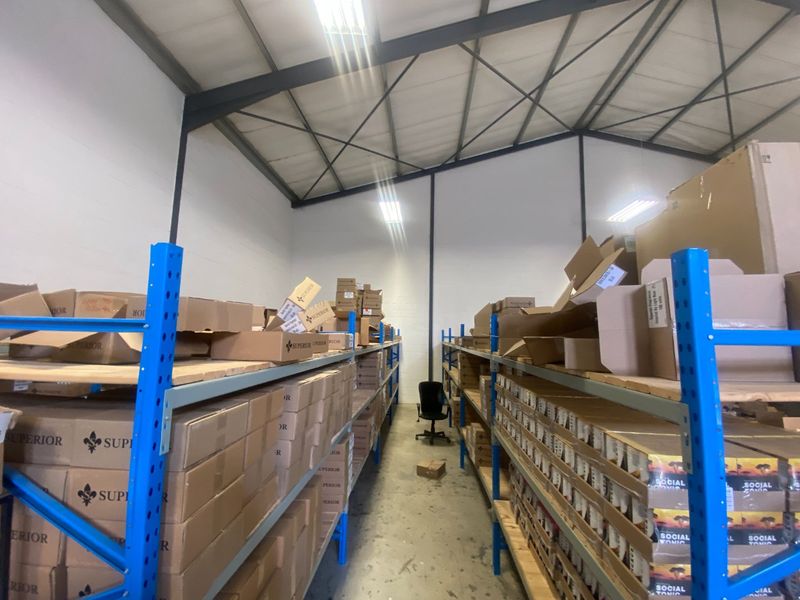 Commercial warehouse storage area featuring heavy-duty industrial steel racking, exposed roof trusses, and durable concrete flooring.