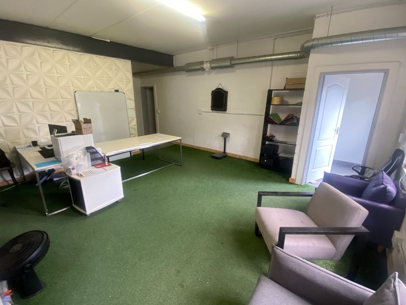 Commercial office space featuring exposed ventilation ducting, a textured feature wall, and direct access to an adjoining room.