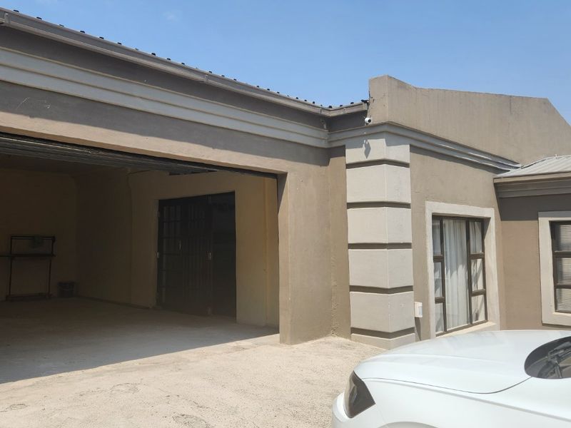 Front view of the property featuring a garage entrance, concrete driveway, and exterior facade with aluminium window frames.