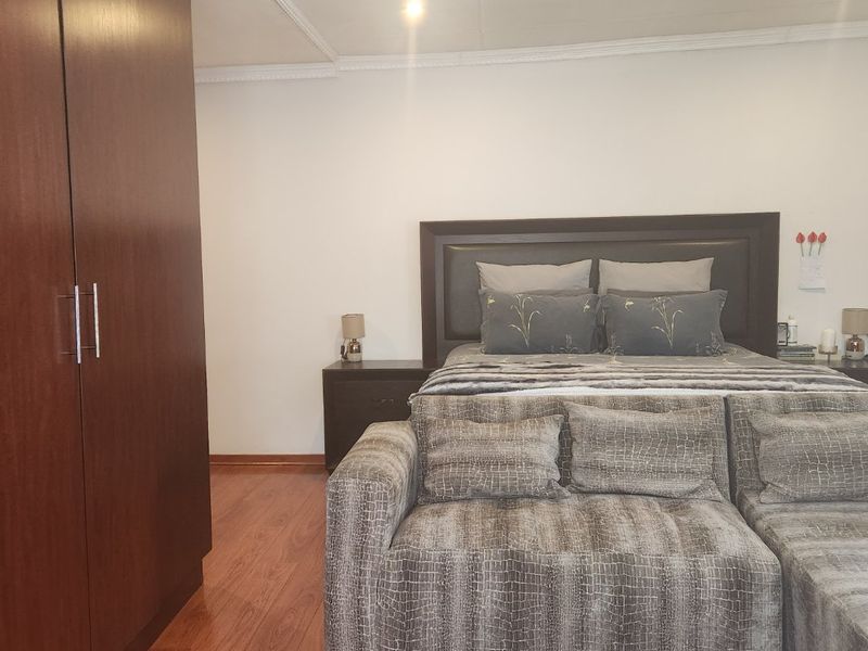 A well-maintained bedroom featuring laminate flooring, crown molding, and a large built-in wardrobe.