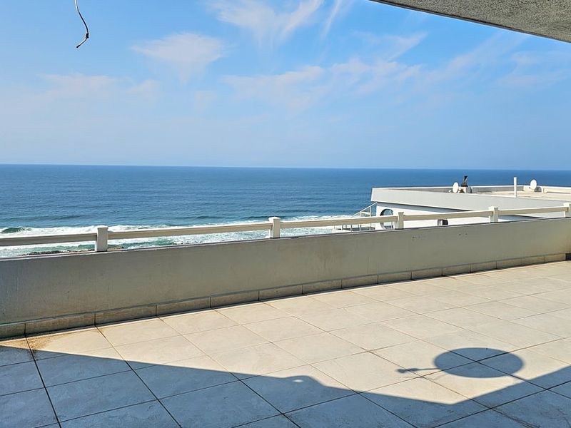 Spacious balcony featuring tiled flooring and a protective railing, offering expansive, unobstructed ocean views.