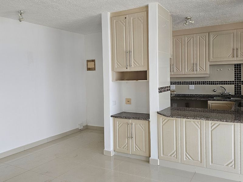 Open plan kitchen and living area featuring neutral cabinetry, granite countertops, and tiled flooring throughout.