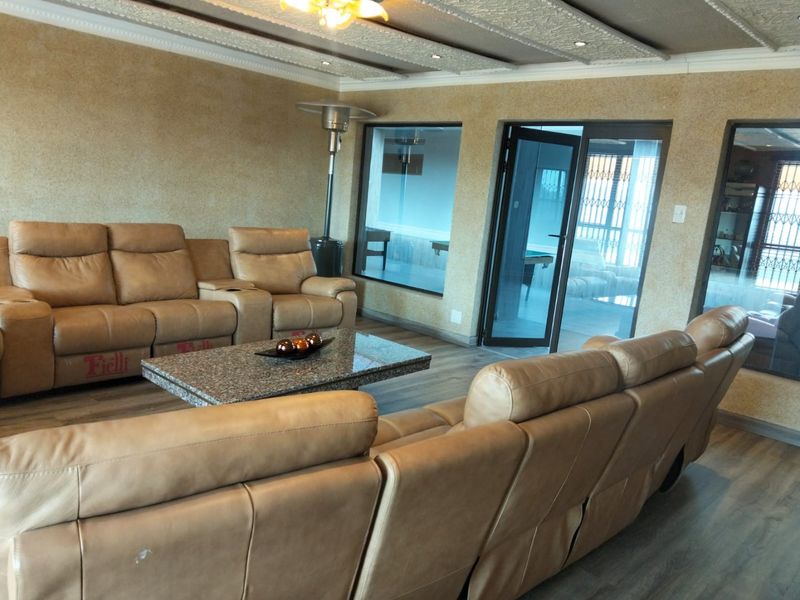 Spacious living room featuring textured walls, a decorative coffered ceiling with recessed lighting, laminate flooring, and direct access to an outdoor area via glass doors.