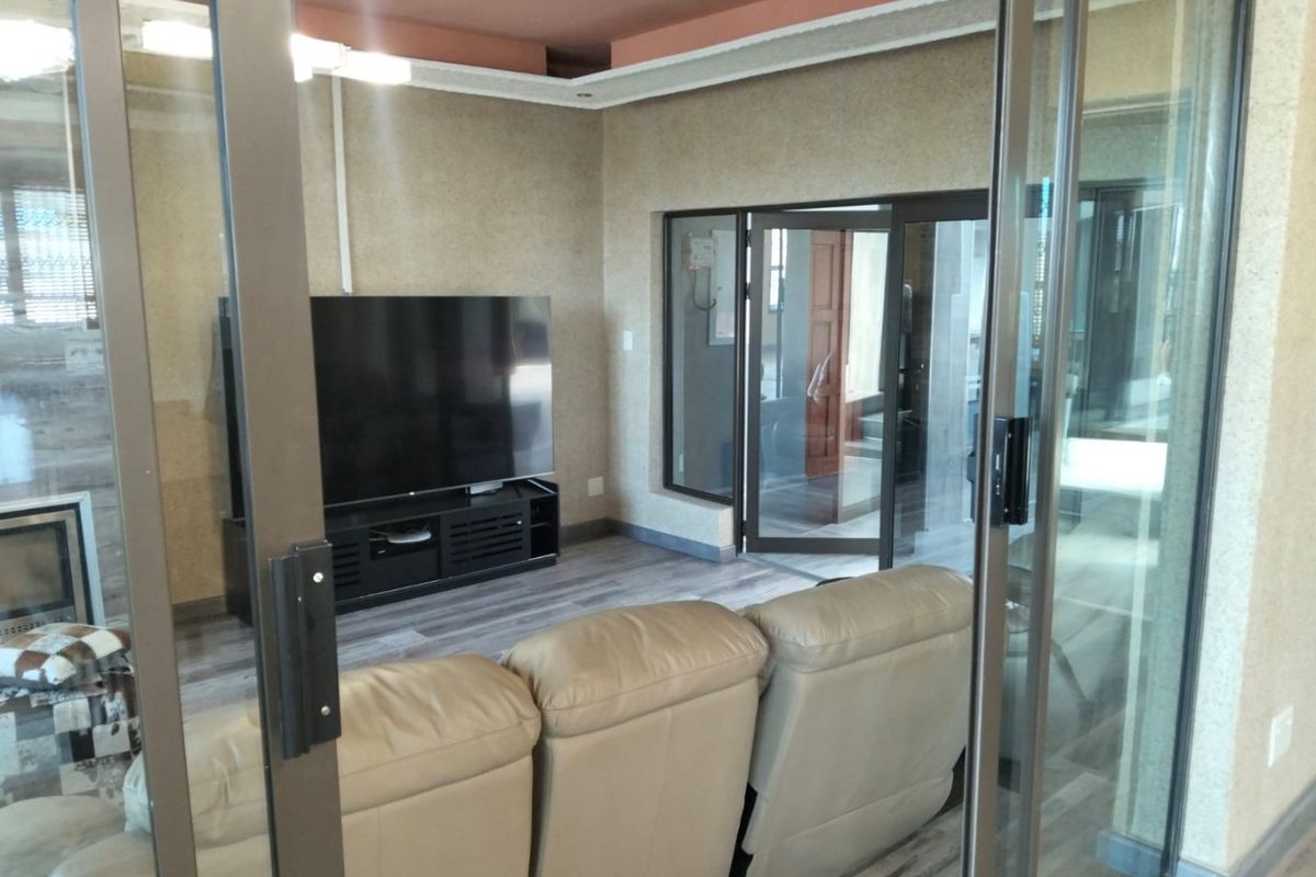 A living room featuring laminate flooring, a recessed ceiling, and sliding glass doors that provide access to the adjacent area.