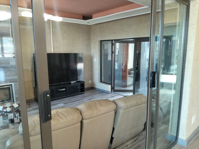 A living room featuring laminate flooring, a recessed ceiling, and sliding glass doors that provide access to the adjacent area.
