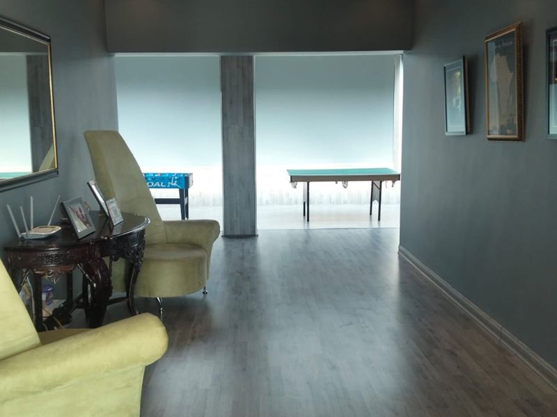 A spacious living area featuring modern laminate flooring, recessed ceiling lighting, and a unique decorative circular ceiling feature.