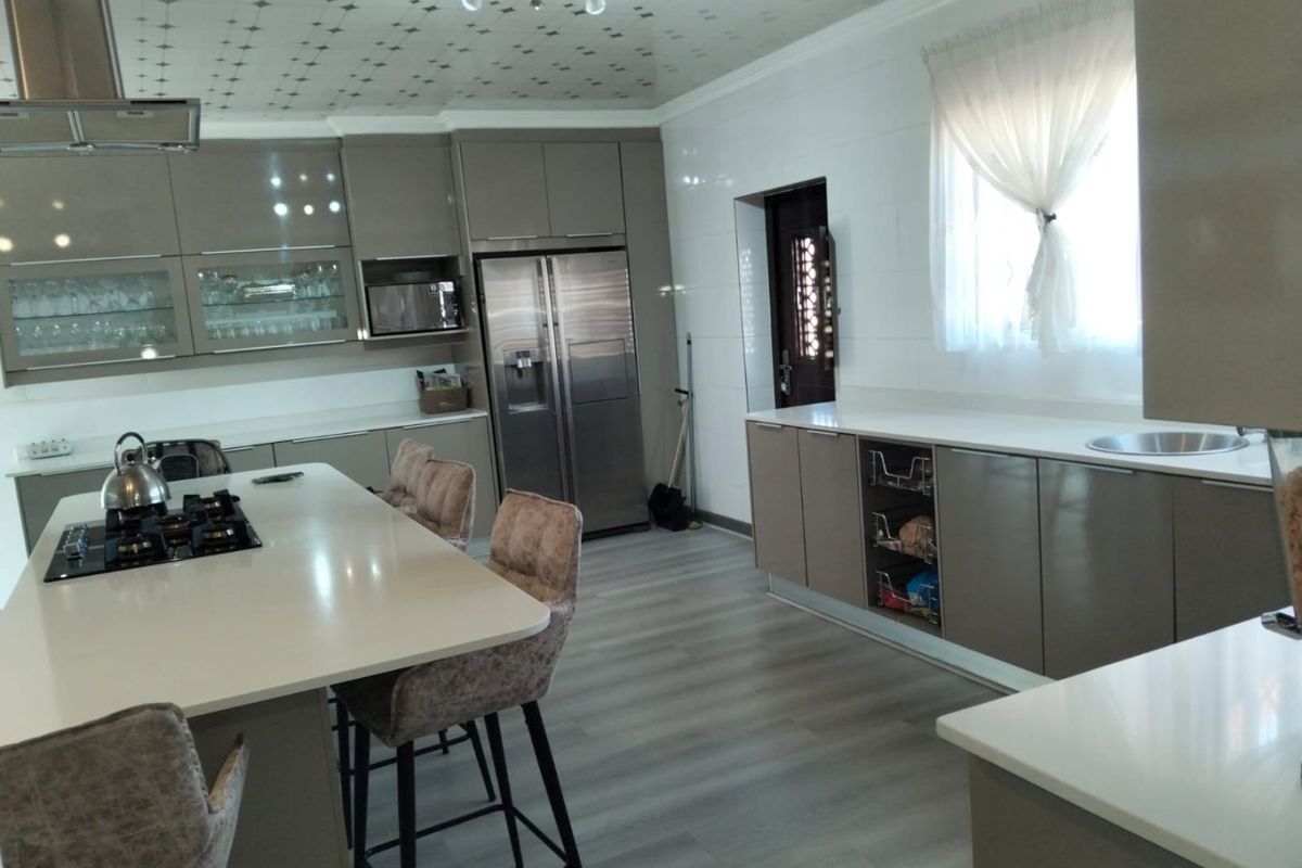 Modern kitchen featuring a central island with gas hob, sleek cabinetry, quartz countertops, and integrated appliances, finished with contemporary laminate flooring.