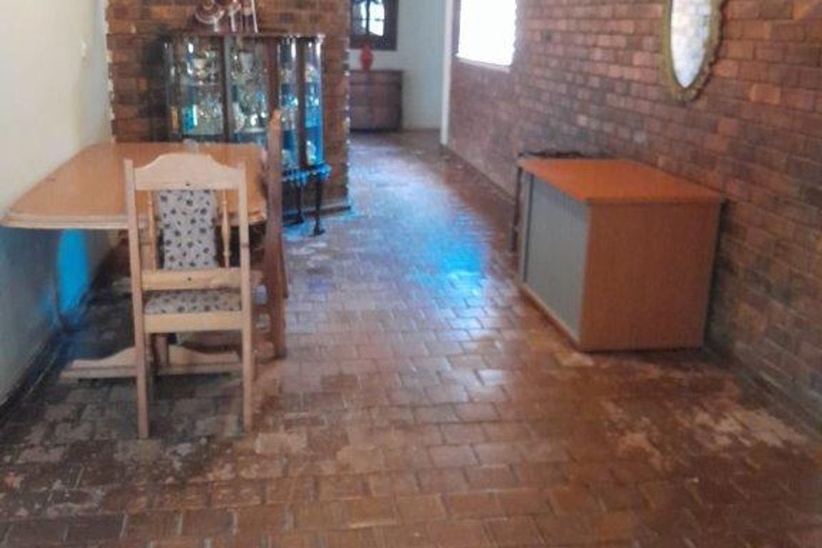 Living area featuring rustic exposed brick walls and traditional terracotta tile flooring, offering a character-filled space with potential for modernization.