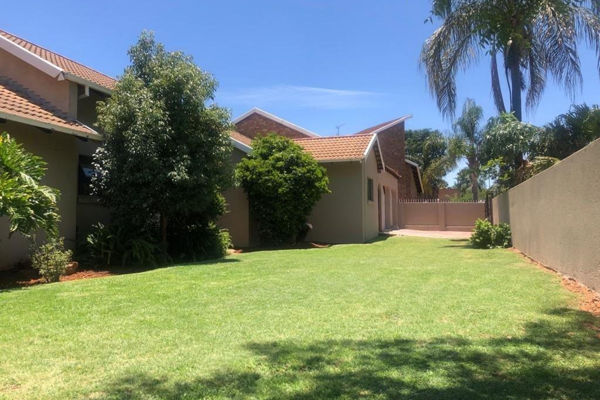A well-maintained rear garden featuring a spacious lawn, established landscaping, and secure boundary walls, providing a private outdoor space.