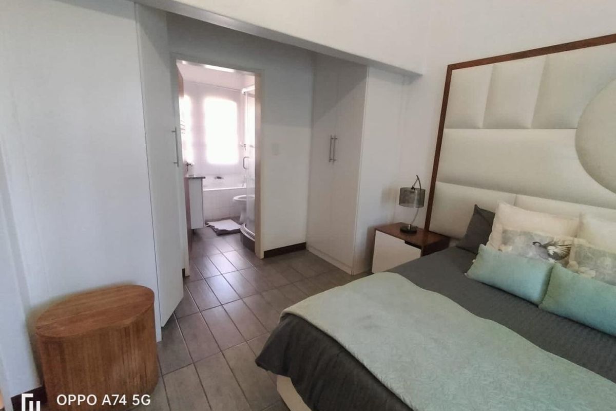 A bedroom featuring tiled flooring and built-in cupboards, with an adjoining en-suite bathroom.