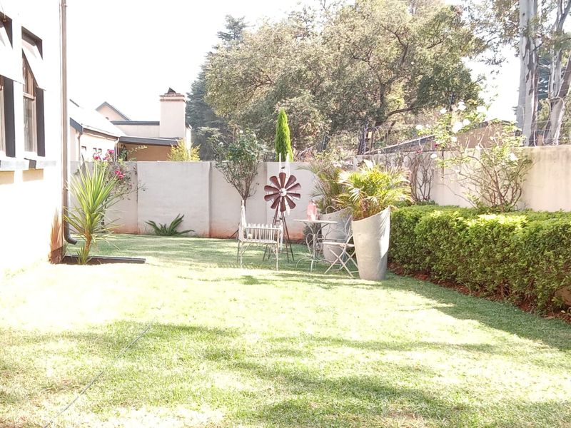 A private rear garden featuring a well-maintained lawn, established hedging, and a solid boundary wall, providing a peaceful outdoor space.