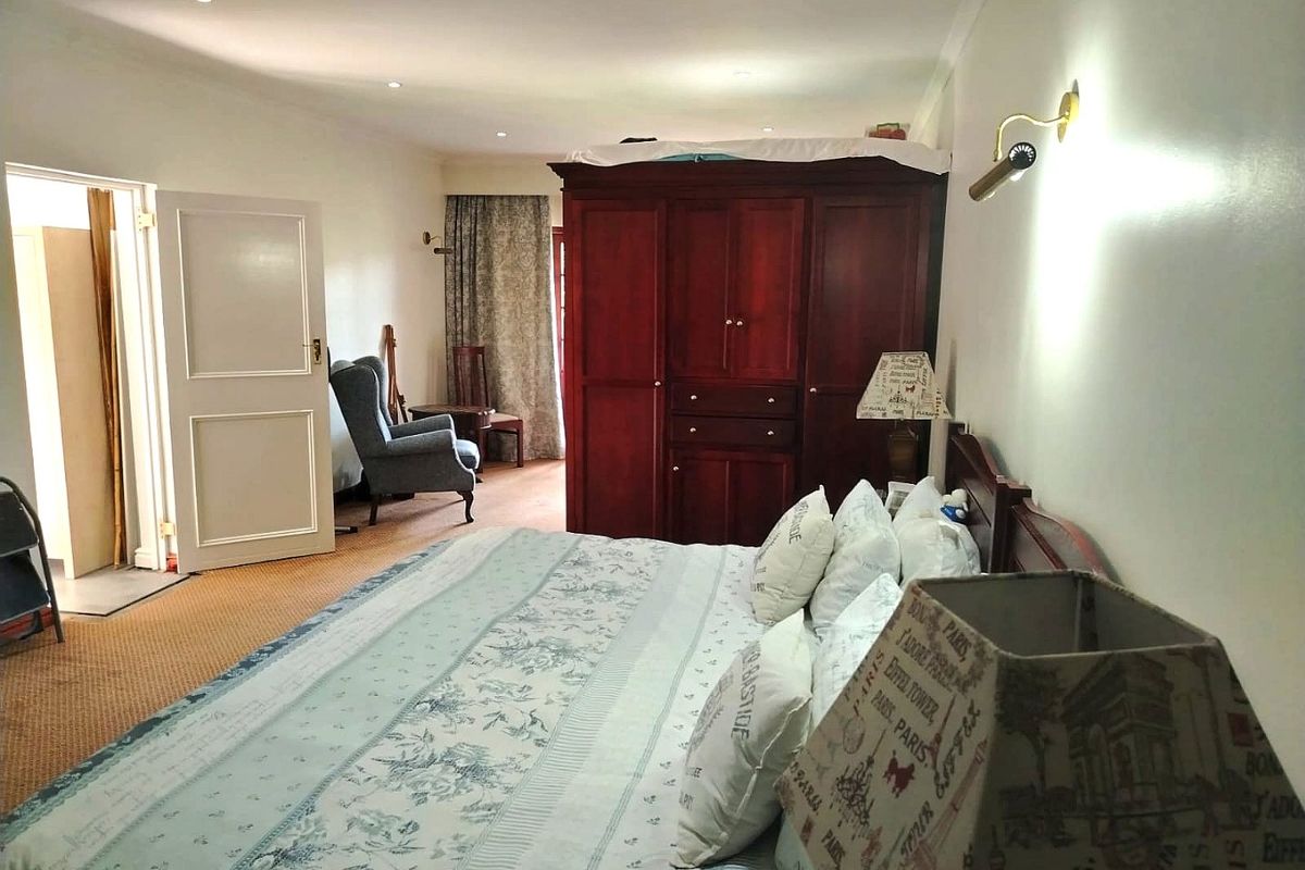A spacious bedroom featuring carpeted flooring, recessed downlighting, and wall-mounted light fixtures, providing a functional and comfortable living space.