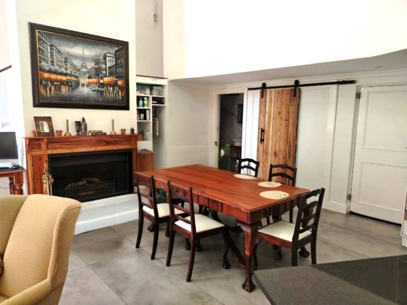 Dining area featuring a fireplace with a wooden mantelpiece, tiled flooring, and a rustic sliding barn door leading to an adjacent space.