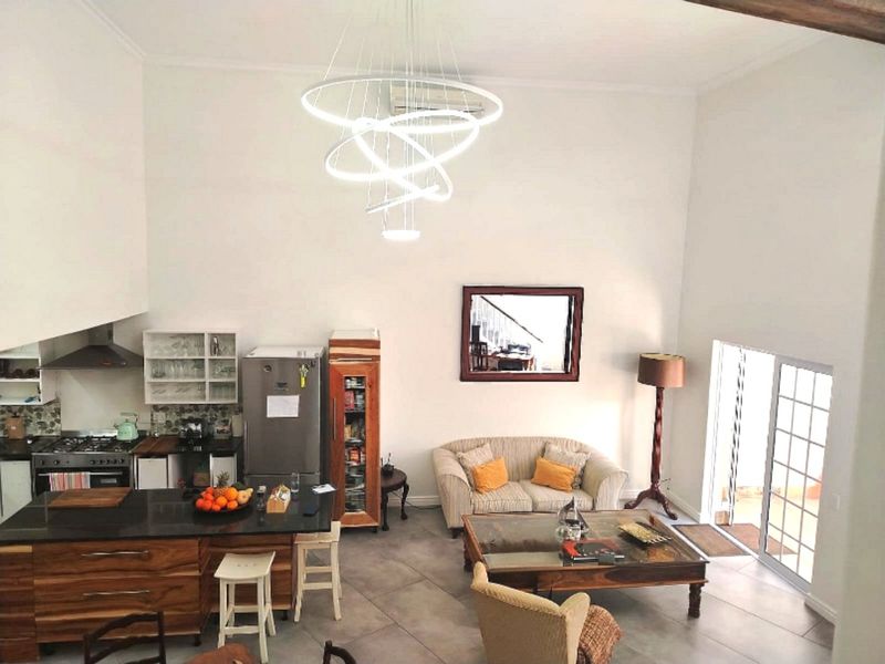 Spacious open-plan living area featuring a modern kitchen with a central island, gas hob, and tiled flooring, leading to a bright living space.