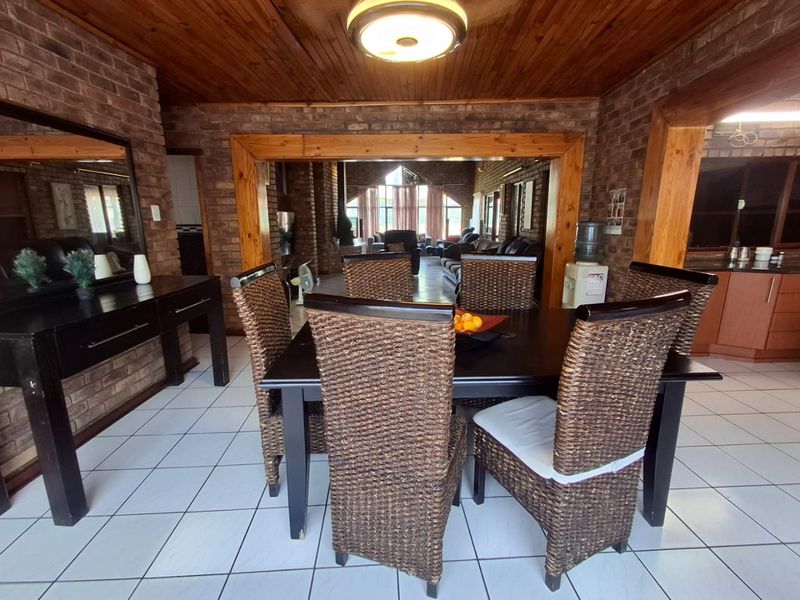 Open plan dining area featuring exposed brick walls, timber ceiling, and ceramic tiled flooring, flowing into the adjacent living space.