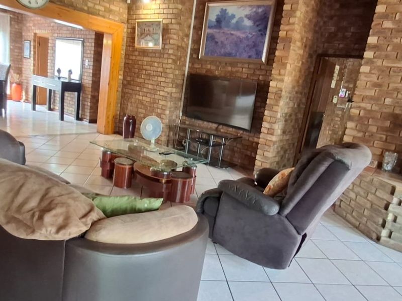 Spacious living room featuring exposed brick walls, tiled flooring, and a built-in fireplace, creating a warm and rustic atmosphere.