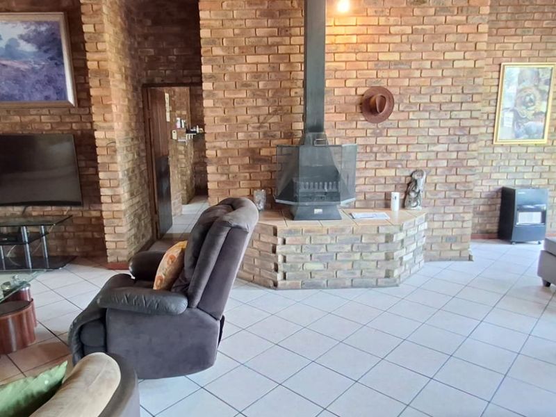Spacious living room featuring exposed brick walls, tiled flooring, and a central freestanding fireplace with a brick hearth.
