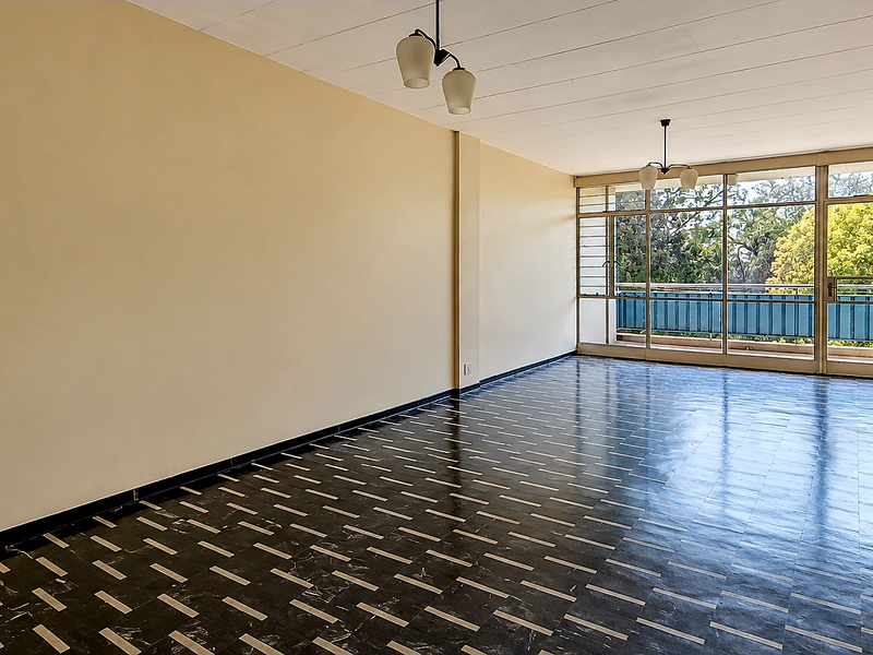 A spacious, empty living room featuring patterned tiled flooring, neutral walls, and large sliding glass doors leading to an outdoor balcony area.