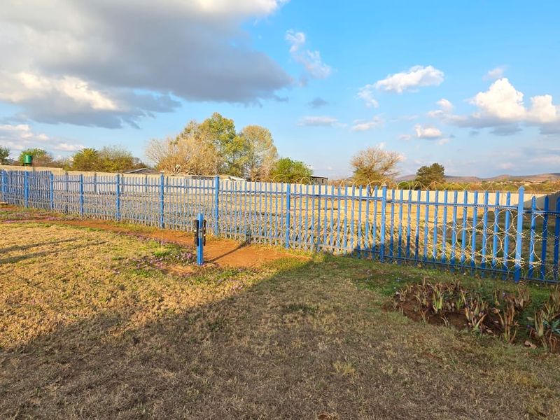 A spacious outdoor area featuring secure steel palisade fencing with razor wire, enclosed by a perimeter wall, suitable for commercial development or storage.
