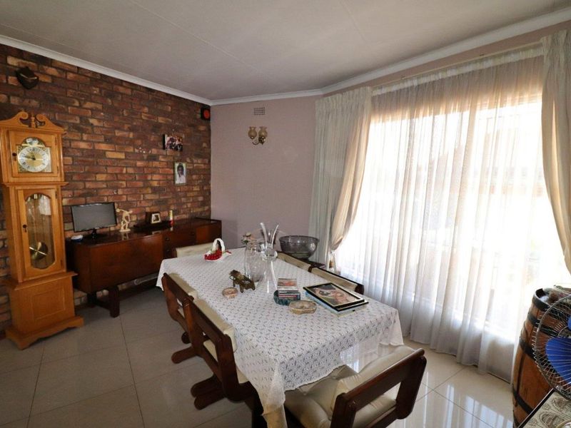 Dining room featuring an exposed brick accent wall, tiled flooring, and large windows allowing for natural light.