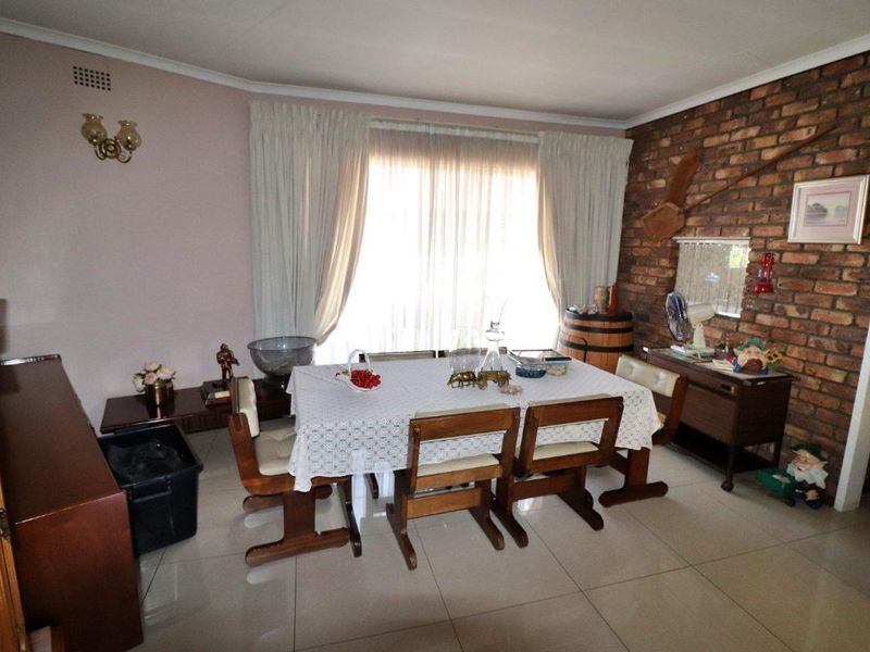 A dining room featuring a prominent exposed brick wall, neutral tiled flooring, and a coved ceiling, offering a classic foundation for interior updates.