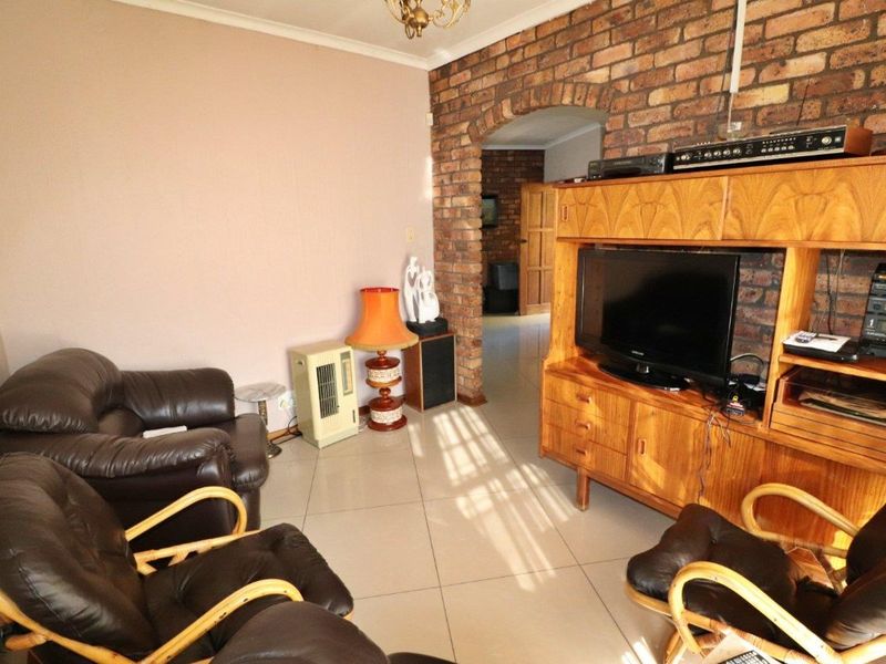 Living room featuring an exposed brick feature wall with a decorative brick archway and neutral tiled flooring.