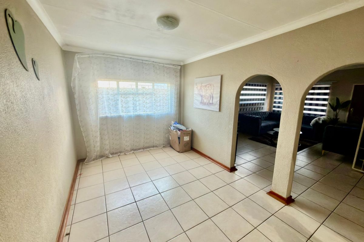 An empty living area featuring ceramic floor tiles and distinctive arched doorways leading to an adjacent space.