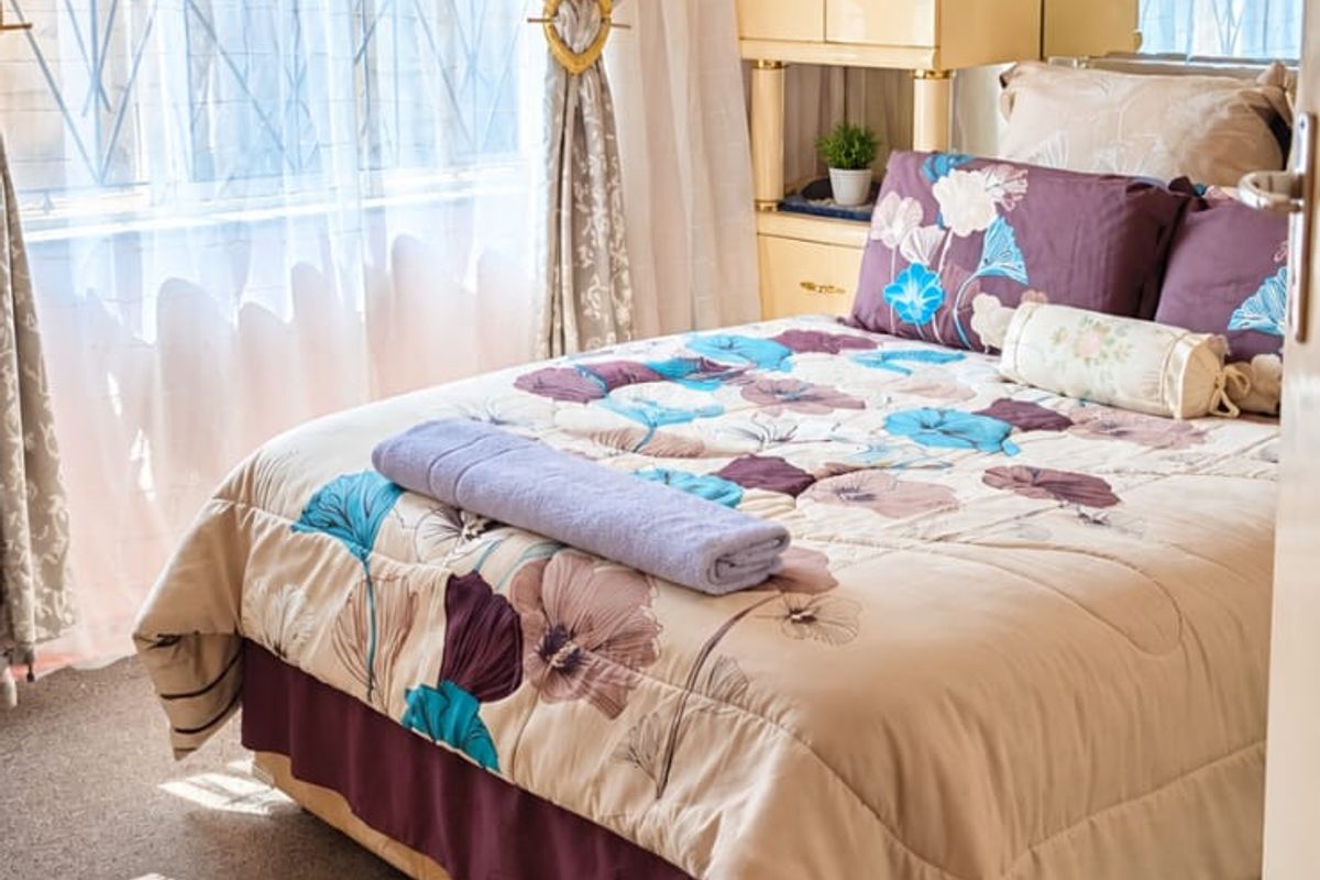 A cozy bedroom featuring a built-in wardrobe, decorative ceiling rose, and an elegant crystal chandelier, providing a classic and functional living space.