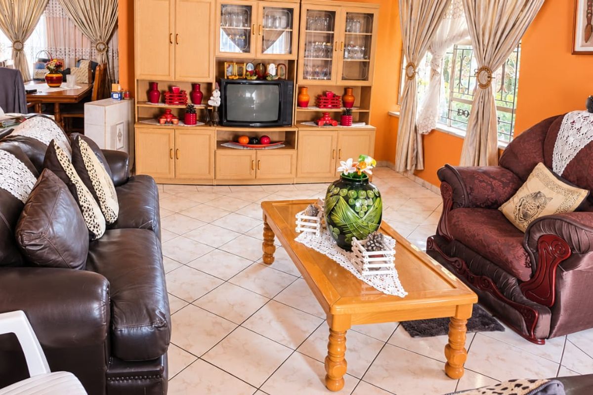 A living room featuring tiled flooring and built-in wooden cabinetry, offering a functional space with traditional finishes.
