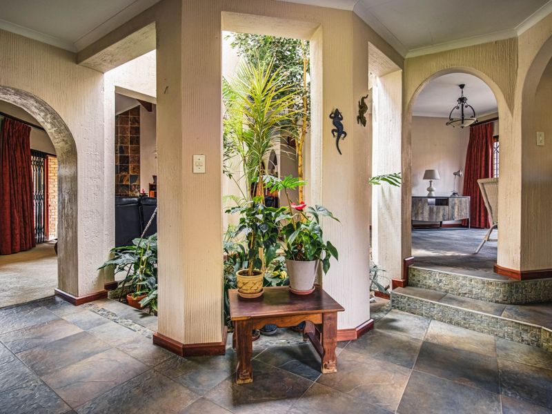 A spacious hallway featuring unique architectural arched doorways, tiled flooring, and a central atrium area that connects multiple living spaces.