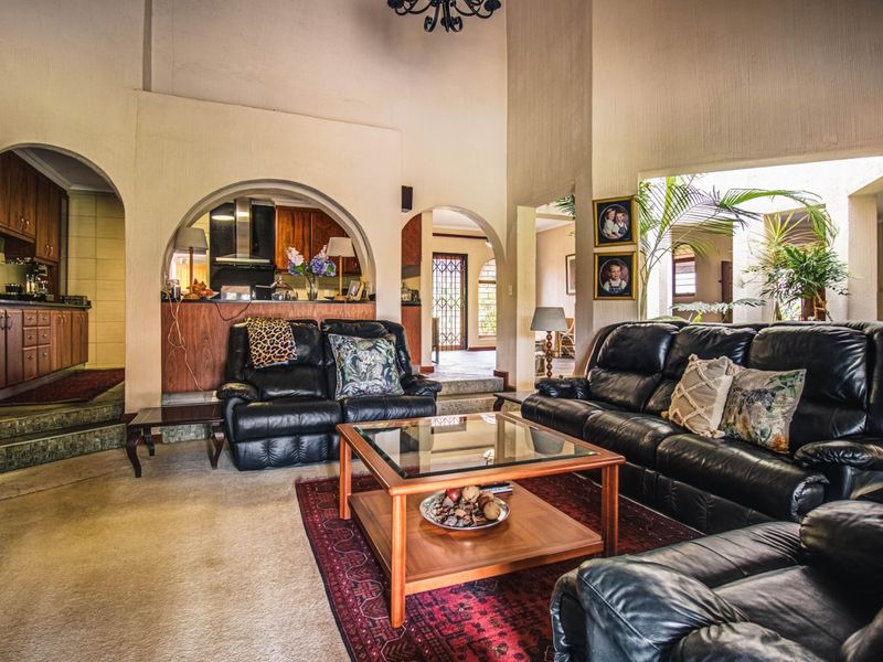Spacious open-plan living area featuring high vaulted ceilings, arched architectural details, and a connected kitchen with built-in cabinetry.
