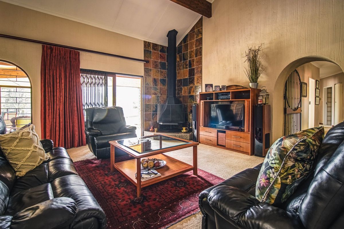 Spacious living room featuring a vaulted ceiling with exposed timber beam, a tiled fireplace surround with a freestanding fireplace, and arched architectural details.