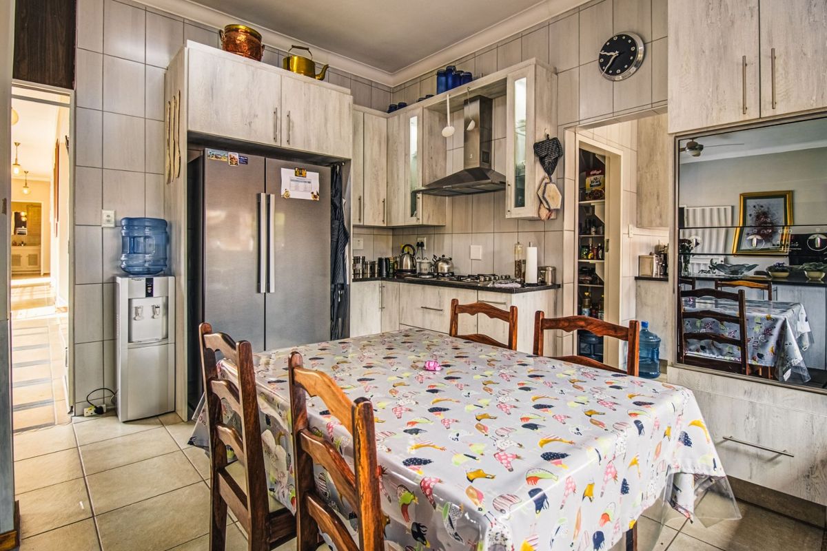 A functional kitchen featuring built-in cabinetry, a gas hob with extractor fan, tiled splashbacks, and an adjoining pantry area.