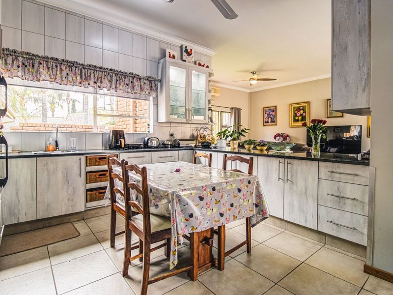 Open-plan kitchen and dining area featuring light-toned cabinetry, granite countertops, tiled flooring, and a functional layout with integrated storage.