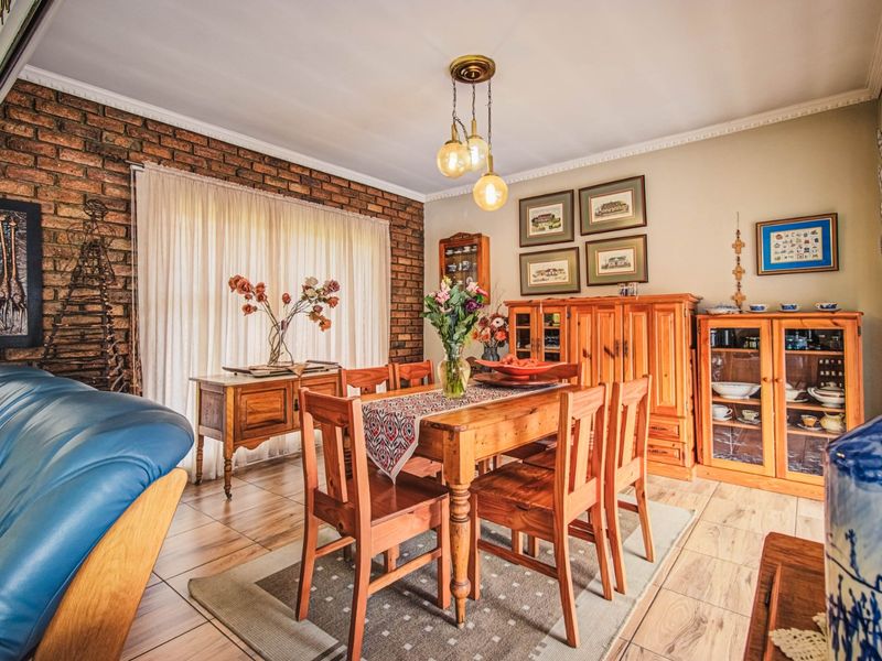 A well-maintained dining room featuring an exposed brick feature wall, ceramic tile flooring, and decorative pendant lighting.
