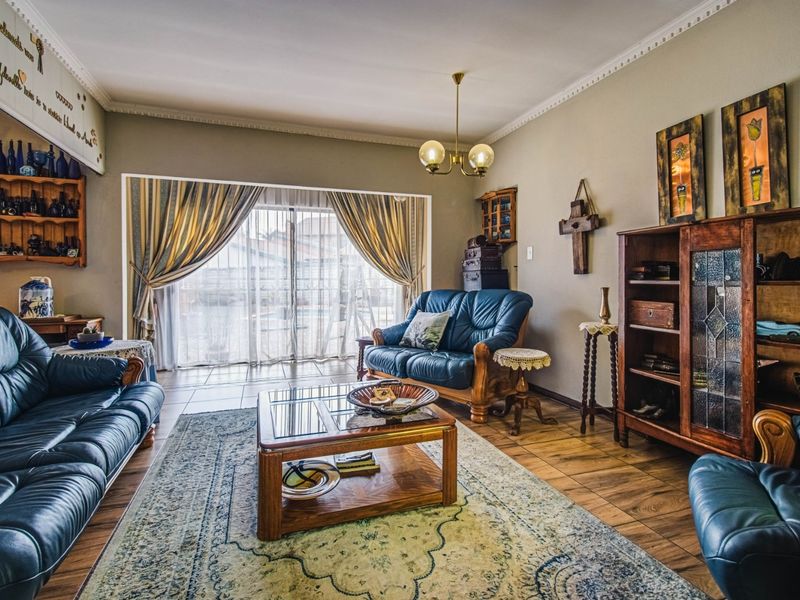A spacious living room featuring tiled flooring, crown molding, and a large sliding glass door providing natural light and access to the exterior.