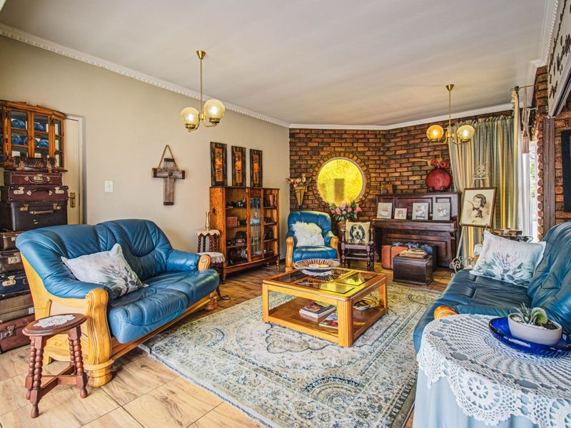 A cozy living room featuring an exposed brick wall, a unique circular window, crown molding, and tiled flooring.
