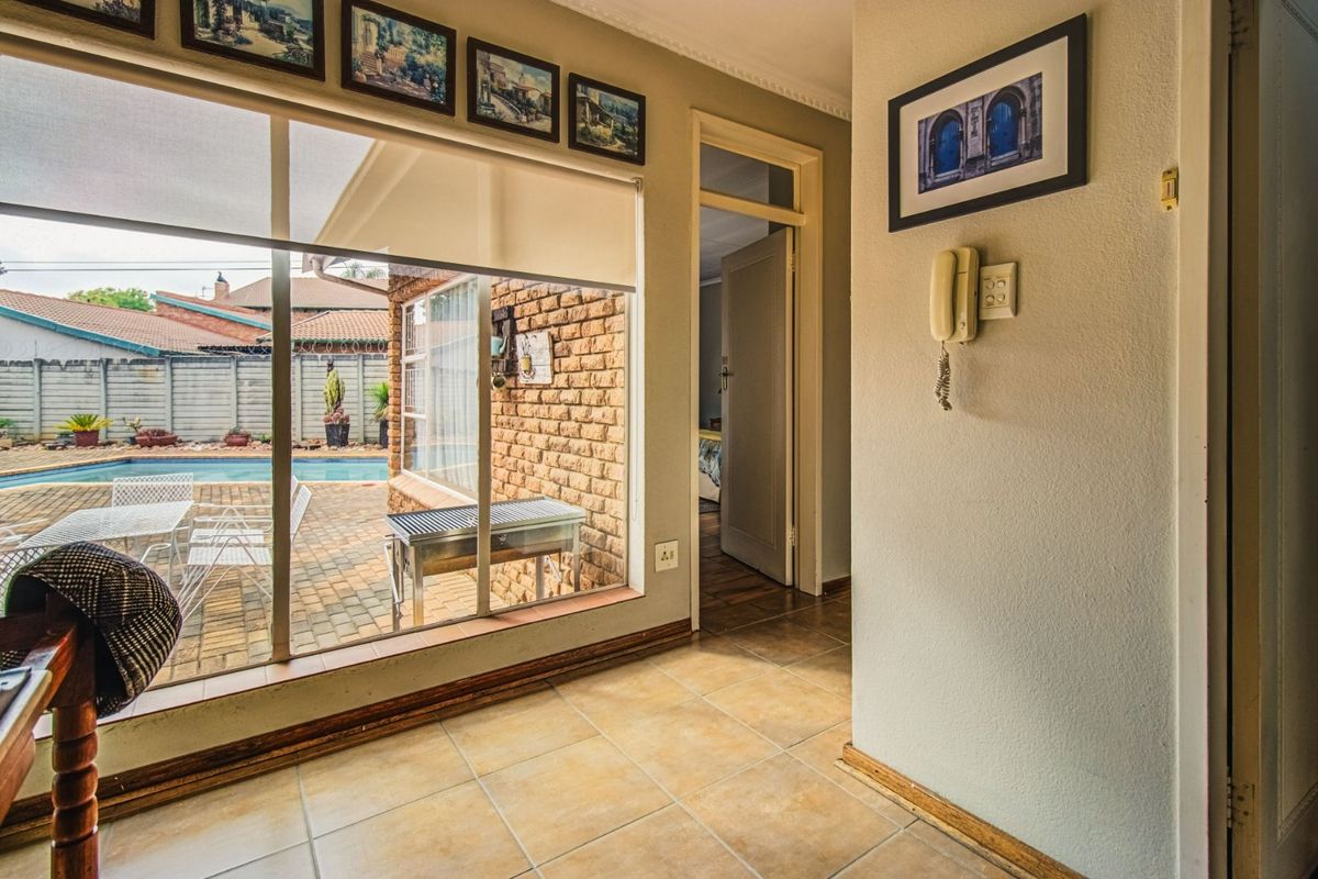 Interior living space featuring tiled flooring, large windows with pool views, and an intercom system, providing a bright connection to the outdoor area.