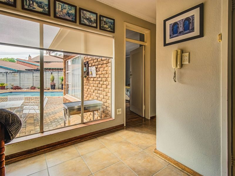Interior living space featuring tiled flooring, large windows with pool views, and an intercom system, providing a bright connection to the outdoor area.